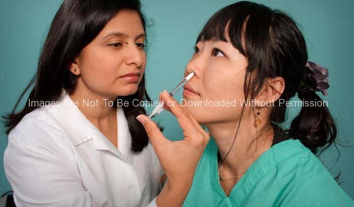 Hispanic Female Nurse Giving Nasal Spray Vaccine to a Patient