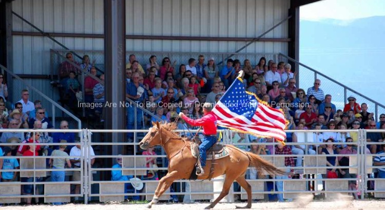 Rodeo cowboy with American flag riding horse